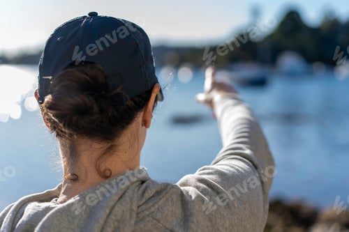 Preview: View from behind of lady with hat on, pointing out to sea