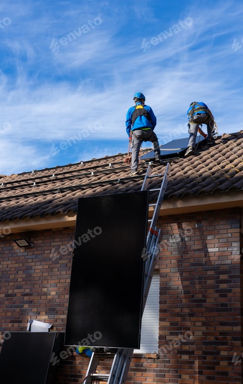 Preview: Workers from a solar panel installation company installing solar panels on the roof of a house