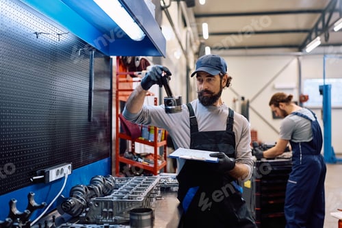 Preview: Car mechanic examining vehicle parts on workbench while working in auto repair shop.