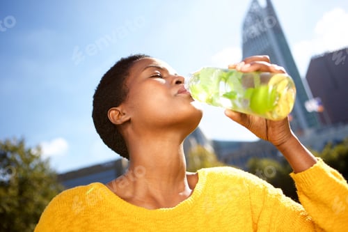 Preview: Close up healthy young black woman drinking water outdoors in park