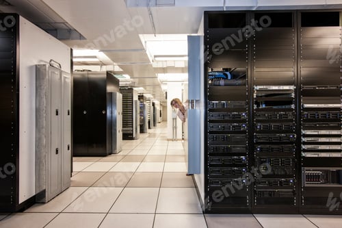 Preview: Computer server room racks with technician in background.