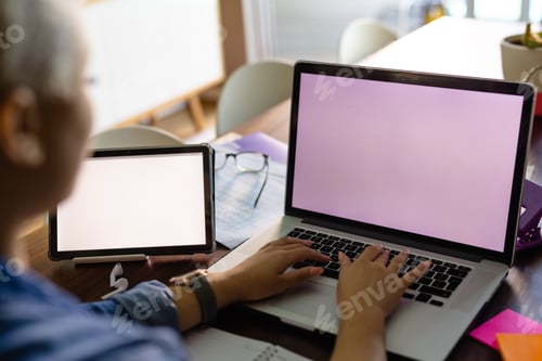 Preview: Unaltered biracial woman working on laptop and tablet with copy space on screens, on table at home
