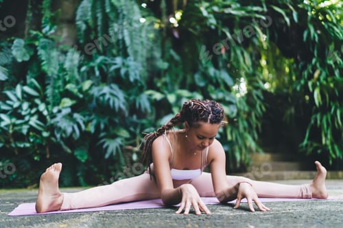 Preview: Caucasian fit girl in sportswear enjoying morning time for doing twine during hatha yoga training