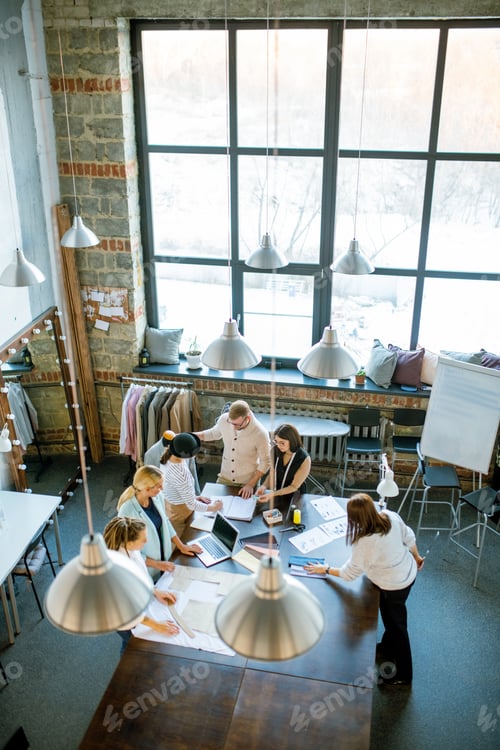 Preview: Group of contemporary creative designers gathered by table in studio