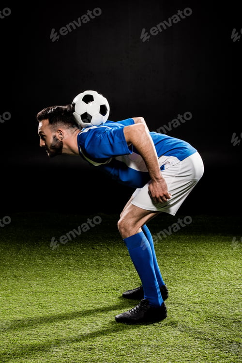 Preview: sportsman in uniform training with ball on grass isolated on black