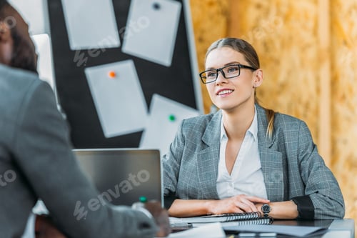 Preview: smiling multicultural businesswoman and businessman talking in office