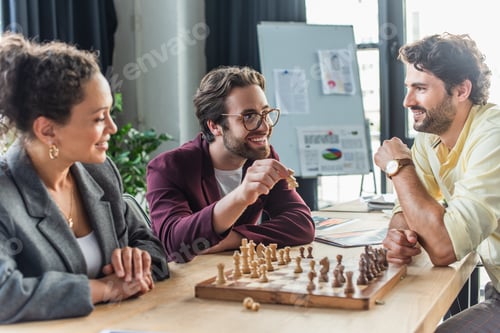 Preview: Positive interracial business people playing chess in office