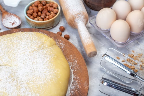 Preview: Front view of raw pastry flour on round board hazelnuts eggs grater on gray background