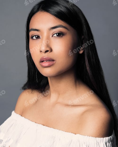 Preview: Portrait of a confident young woman with dark hair on a grey background.