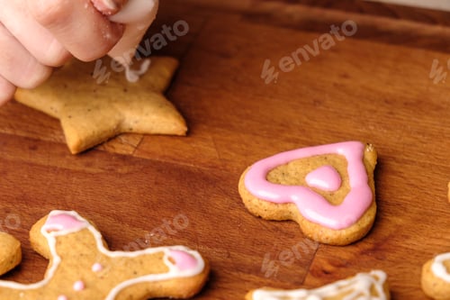 Preview: Icing of Valentines Day. Woman decorating gingerbread cookies in the shape of heart on a wooden