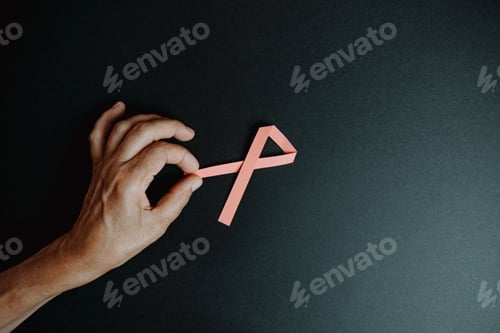 Preview: Old hand grabbing a pink ribbon over a dark background