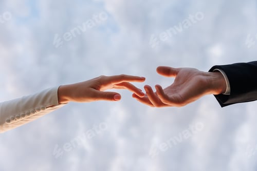 Preview: Hands of bride in white dress and groom in suit reaching each other, touching fingers on blue sky ba