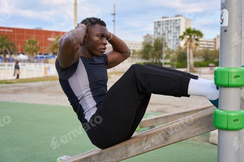 Preview: Black man performing calisthenics sit-ups in an outdoor gym