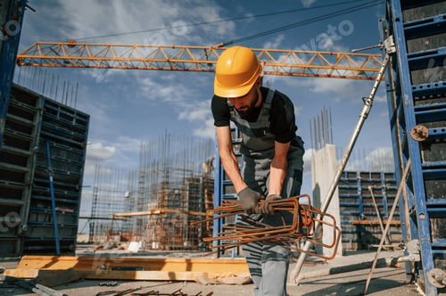Preview: Working with rusty metal pieces. Man in uniform is on the construction site