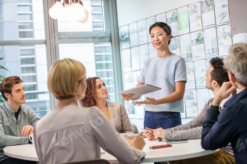 Preview: Female digital designer explaining ideas to team at conference table