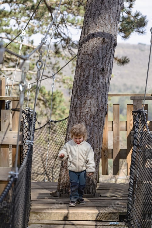Preview: The baby is ready to run over the suspension bridge between the trees