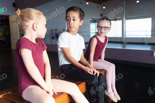 Preview: Cute kids sitting and talking on a bench in a dance studio during class