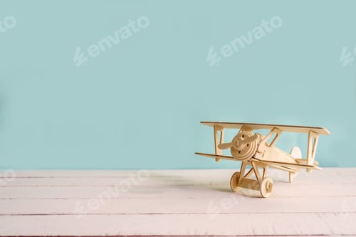 Preview: wooden toy airplane against green background with copyspace