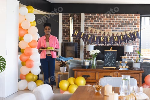 Preview: Smiling woman holding cake at retirement party with festive decorations