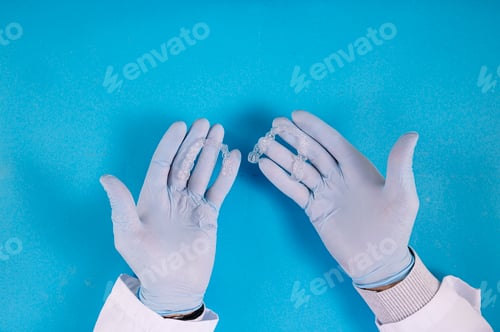 Preview: Doctor hand holding a clear dental aligner with the blue background