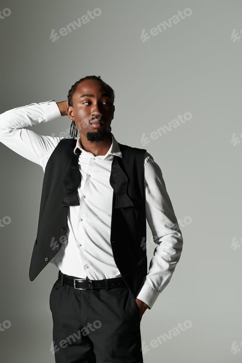 Preview: Stylishly confident young African American man in a suit poses against a grey backdrop