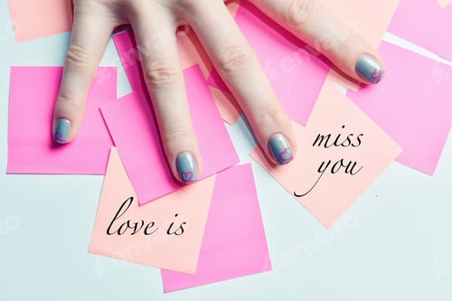Preview: Female hand on the table with blank paper stickers and two with "love is" and "miss you" phrases