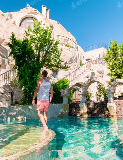 Preview: woman in dress at cave house , guy in infinity pool cave house hotel in the mountains of Cappadocia