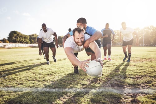 Preview: Caucasian rugby player diving to score a try during a rugby match outside on a field. Young male at