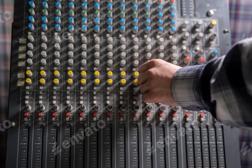 Preview: a Close-Up of a Hand Adjusting the Controls on a Music Mixer Console in a Studio