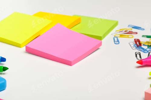 Preview: Sticky notes with markers, colored pens, paper clips laying on a table