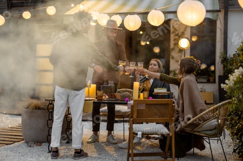 Preview: Young friends dining at backyard of the country house at dusk