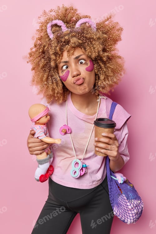 Preview: Vertical shot of funny curly haired woman pouts lips and crosses eyes going to become mother soon