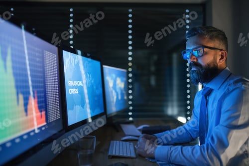 Preview: Businessman with computer sitting at desk, working late. Financial crisis concept