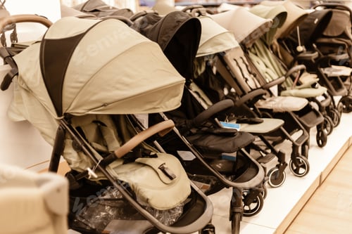 Preview: Multiple strollers are lined up on shelves for sale in a store. Each stroller shows different styles
