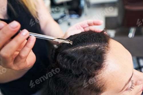 Preview: Close up of woman dropping serum on hair