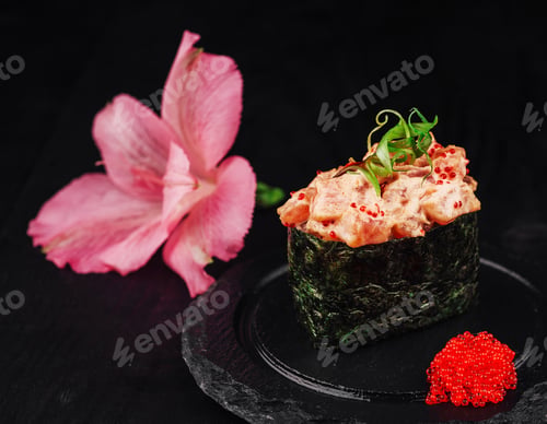 Preview: Gunkan maki sushi standing on a black plate with salmon, tobiko and spicy sauce
