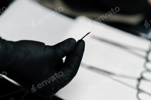 Preview: Piercing studio master holds a needle for piercing in his hands close-up