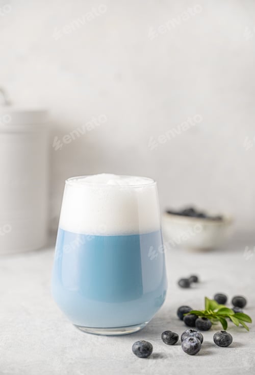 Preview: Blue matcha latte in a glass on a gray concrete background with fresh blueberries.