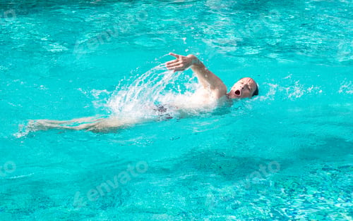 Preview: Mature active man swimming freestyle in outdoor swimming pool under the sun. Healthy lifestyle