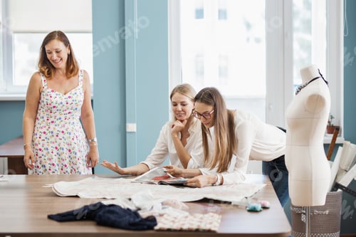 Preview: Three smart-looking pretty women are pointing at the sewing magazine. Tailor's dummy is in the