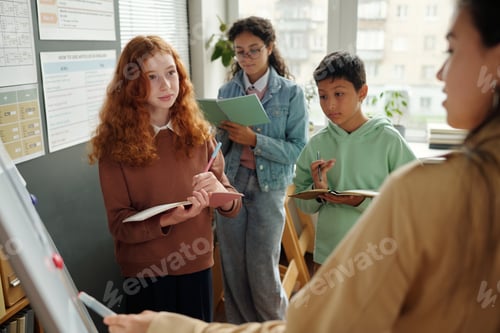 Preview: Group of cute intercultural schoolkids looking at teacher during presentation