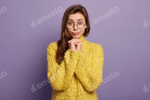 Preview: Waist up shot of pretty brunette female feels lonely and sad, keeps hands under chin, upset by bad n