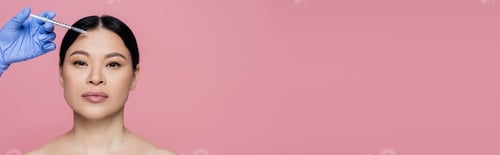 Preview: Beautician holding syringe near face of asian woman with naked shoulders isolated on pink, banner