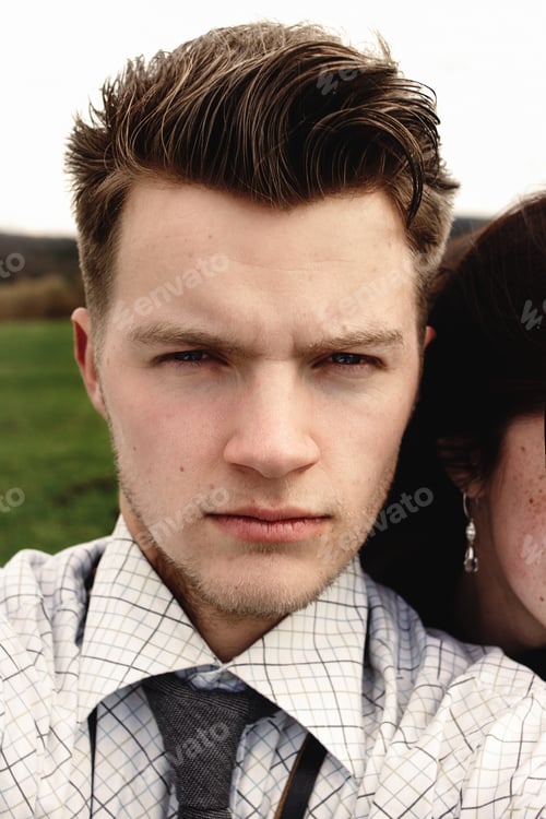 Preview: stylish brunette beautiful woman and man in love having funny selfies in windy spring field
