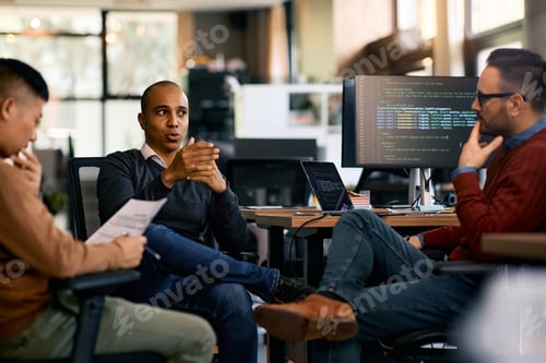 Preview: Group of computer programmers talking while working at IT office.