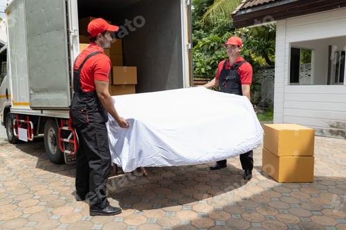 Preview: Portrait of two movers unloading boxes and furniture from a pickup truck.