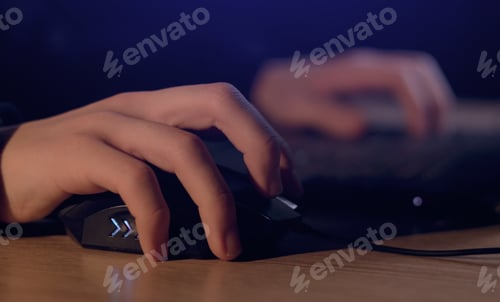 Preview: Close up of man gamer hands using computer mouse is playing video game at night. Male hacker breaks
