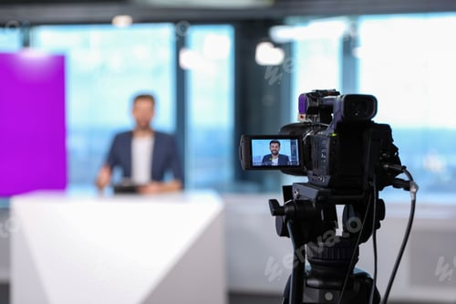 Preview: Presenter working in studio, focus on video camera