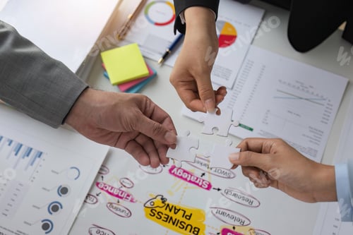 Preview: Closeup top view business team of office worker holding jigsaw puzzle together over table filled