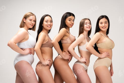 Preview: five smiling multiethnic women in lingerie posing with hands on hips isolated on grey, body